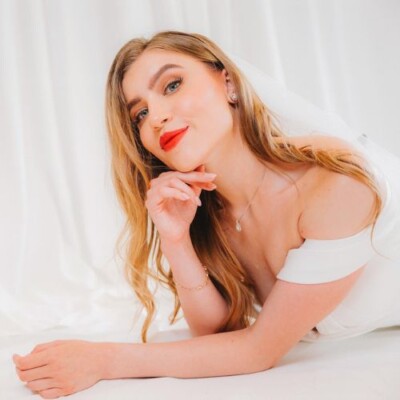 Beauty by Krimse specializes in creating elegant bridal styles Elegant bride with a side bun and intricate jewelry.