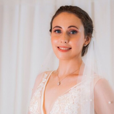 Achieve a flawless bridal complexion with Beauty by Krimse’s expert Bride standing under soft lighting, highlighting her flawless complexion.