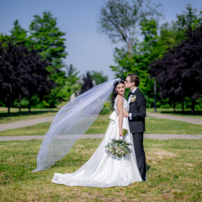 Beauty by Krimse offers expertly styled bridal updos Bride posing elegantly, highlighting her intricate updo and flawless makeup.